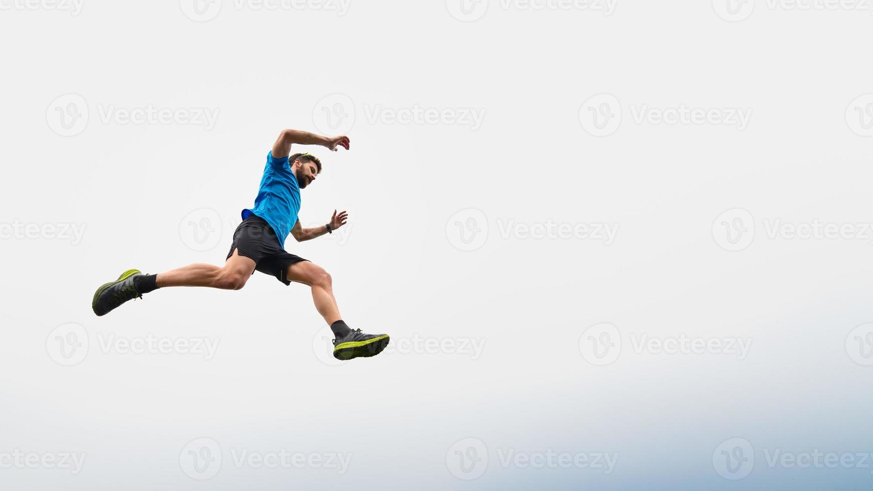 atleta uomo che corre in montagna durante un salto nel cielo foto