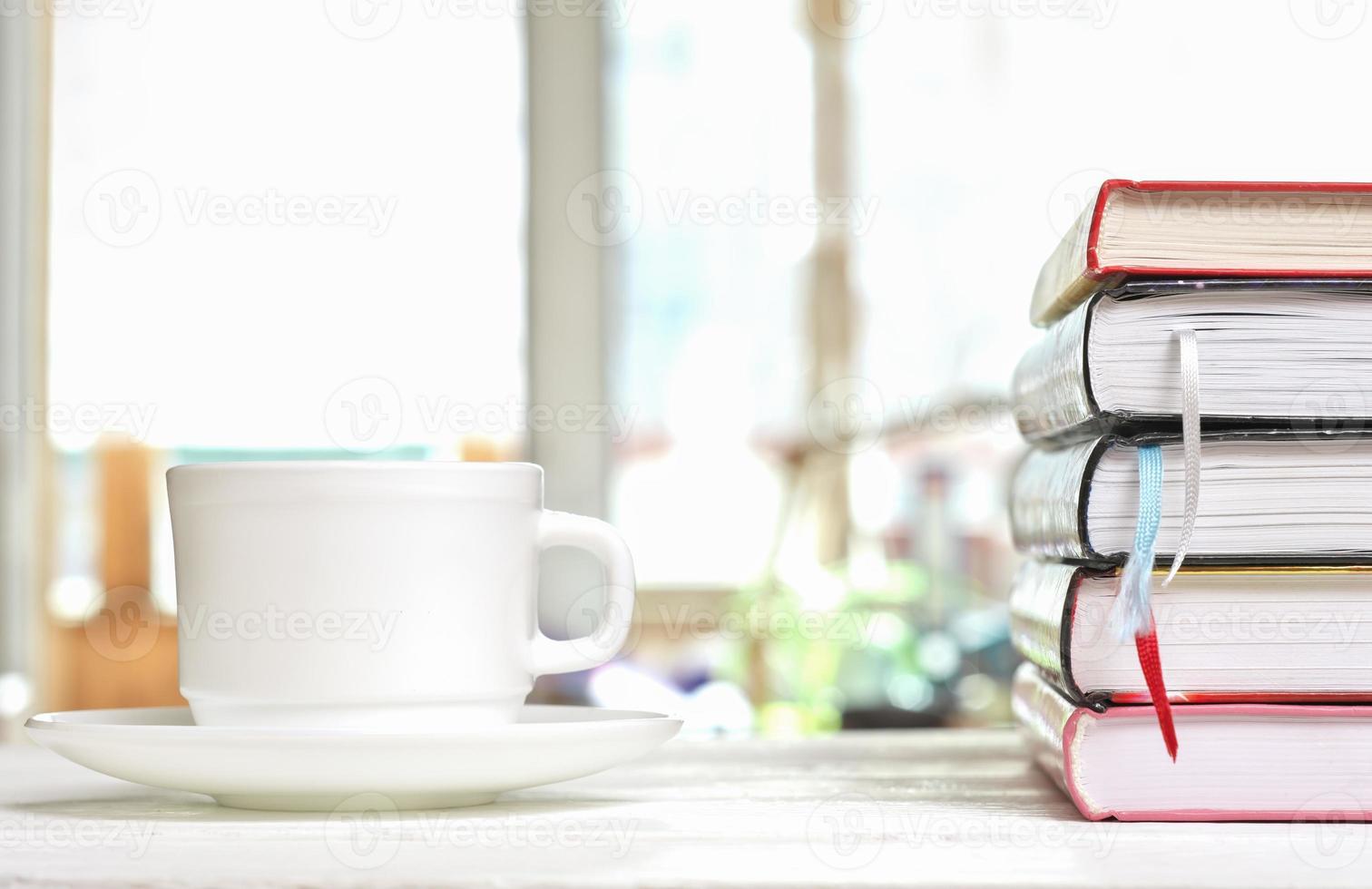 classica tazza di caffè bianca su un tavolo bianco sulla terrazza e una pila di libri con segnalibri. lettura, apprendimento e studio, ore mattutine per l'autoeducazione foto