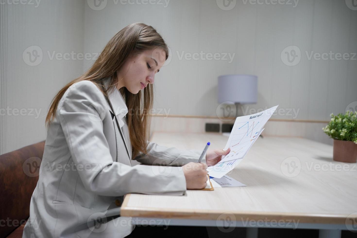 giovane imprenditrice sul posto di lavoro e leggere la carta in ufficio foto