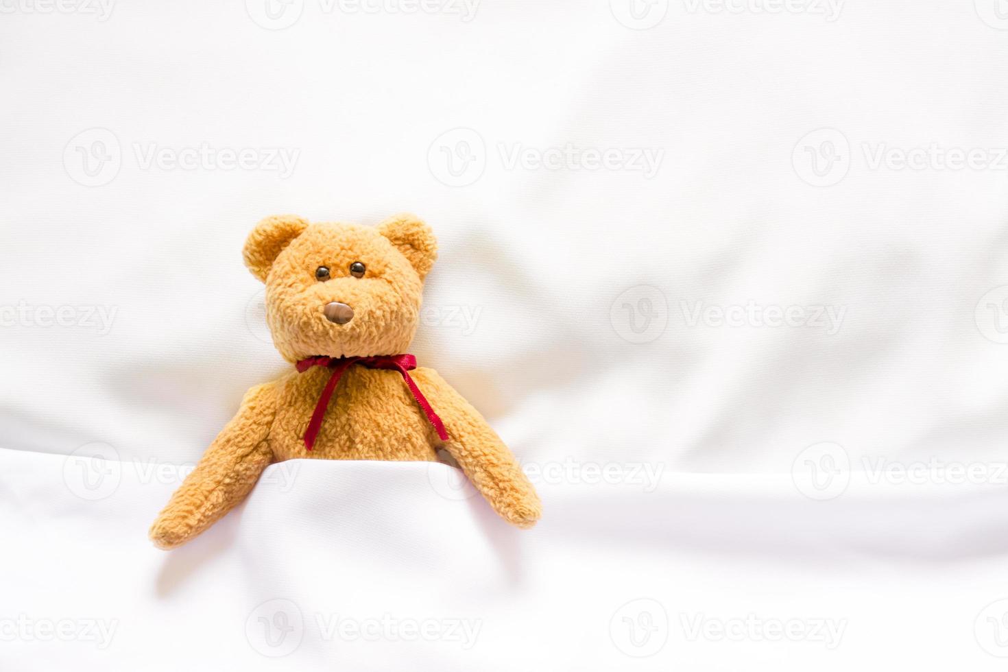 bambola orsacchiotto sdraiata nel letto bianco foto