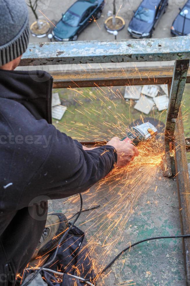 un operaio taglia il metallo con una smerigliatrice. foto