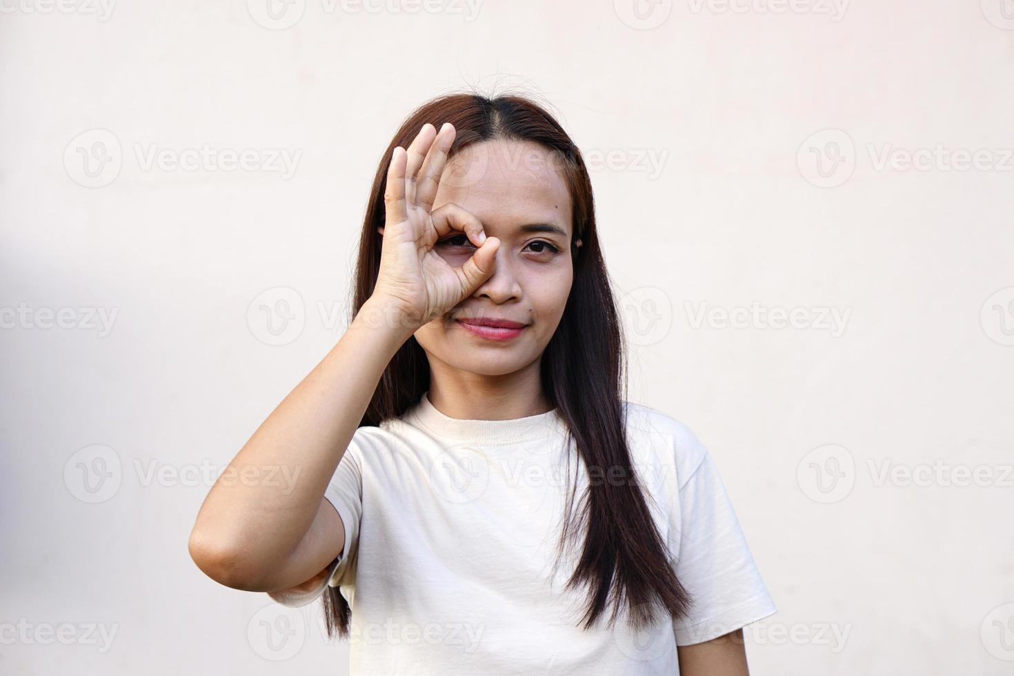 donna asiatica sorridente felicemente alza la mano in segno di ok. foto