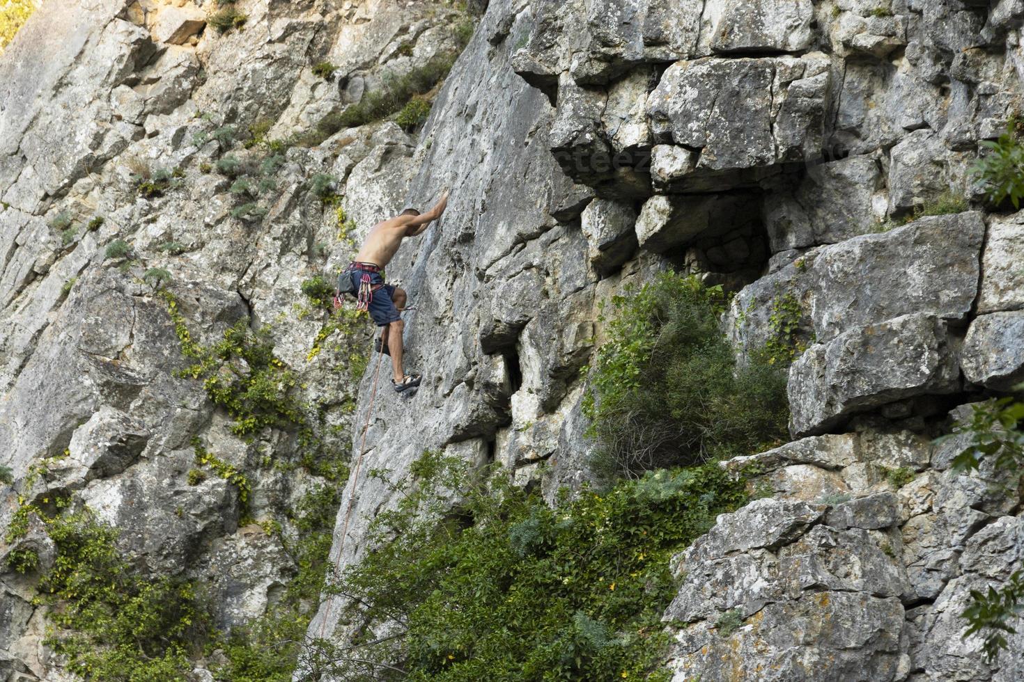 un uomo estremo, uno scalatore su una roccia grigio-rossa a strapiombo nelle montagne della Crimea. foto