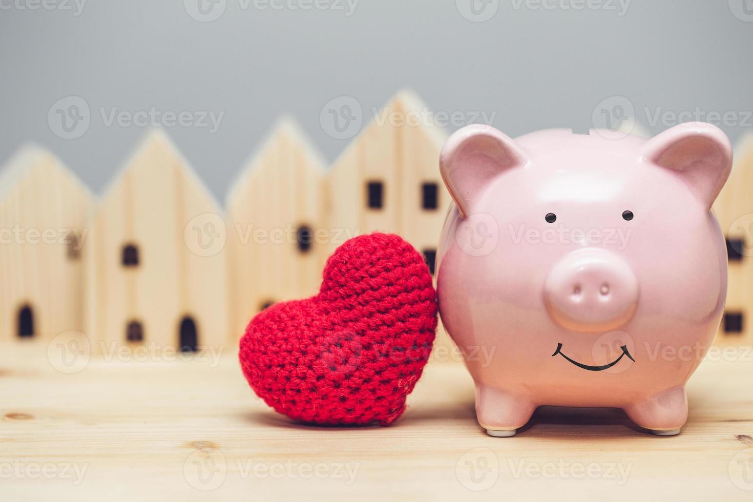 sorriso di maiale carino con cuore rosso sullo sfondo del villaggio di casa per il concetto di casa sicura della comunità d'amore. foto