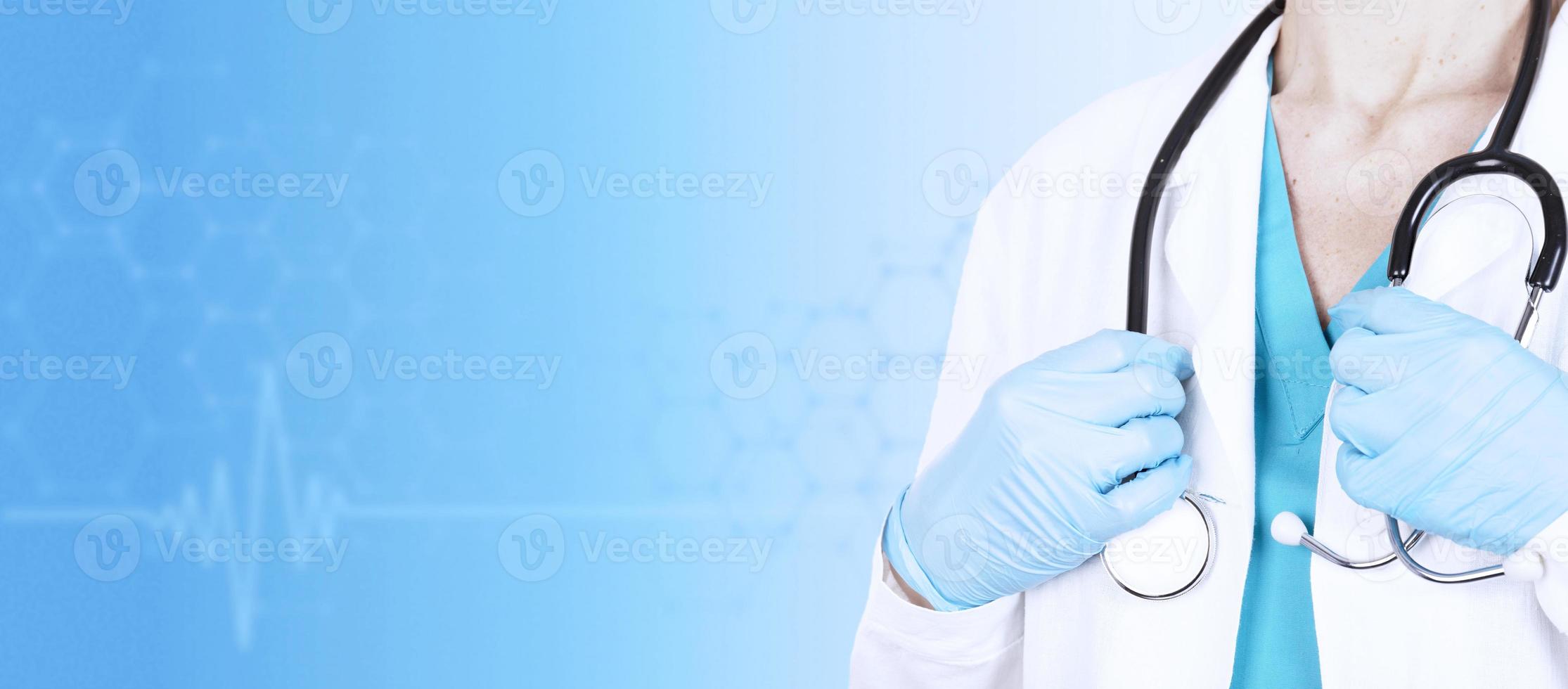 dottoressa in abiti medici con uno stetoscopio in mano su uno sfondo blu medico. vista laterale. bandiera sanitaria. copia spazio. foto