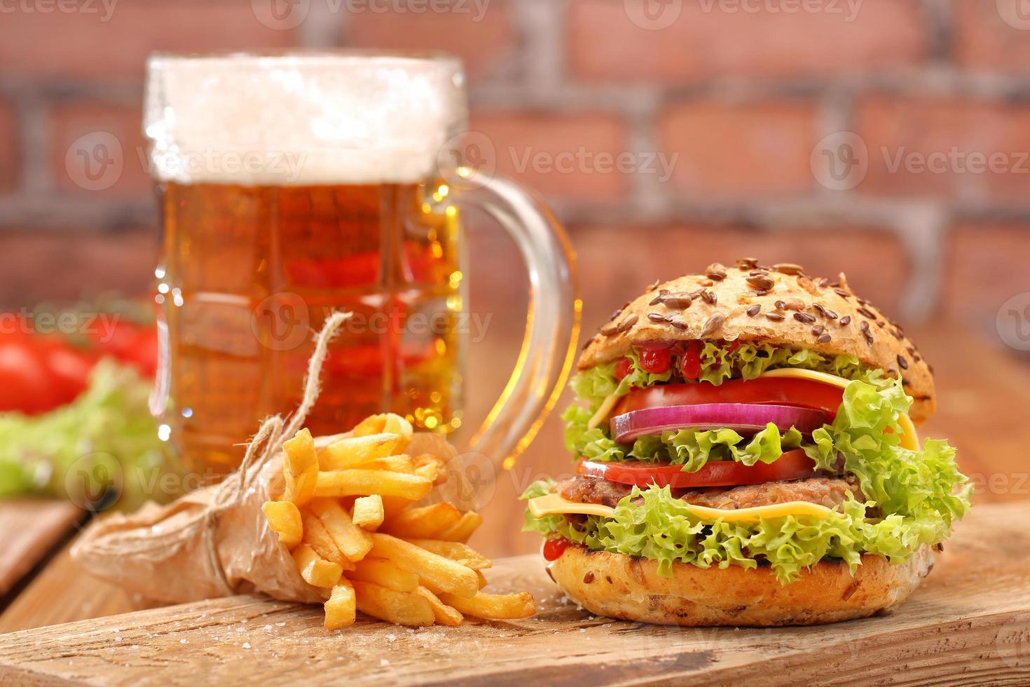 hamburger alla griglia con patatine fritte e birra su sfondo di muro di mattoni foto
