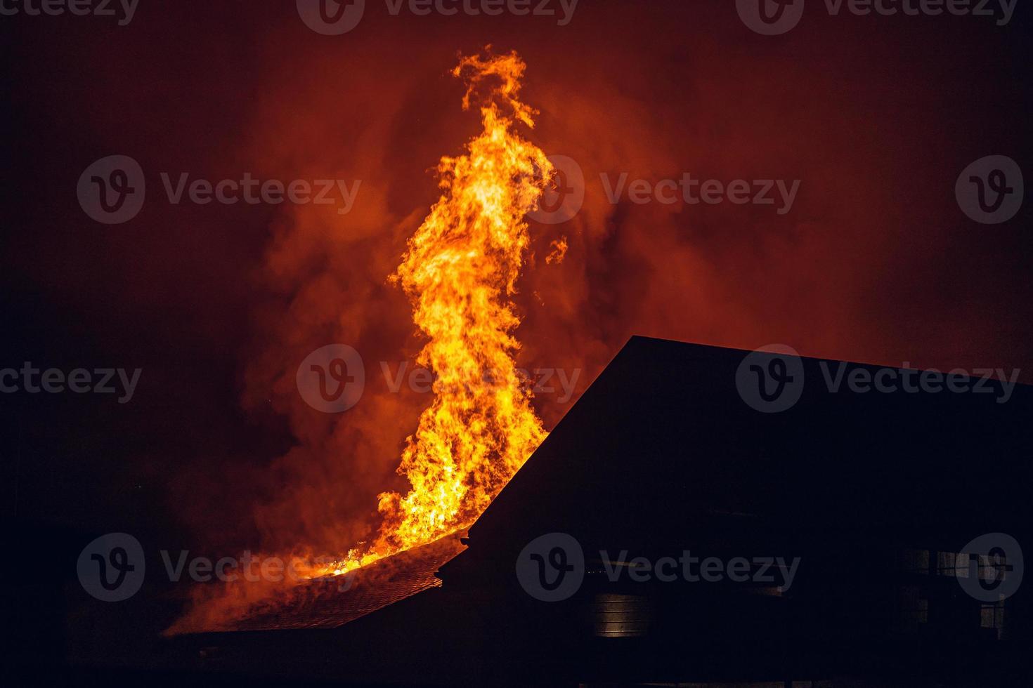 casa in fiamme di notte. forte incendio in un piccolo villaggio foto