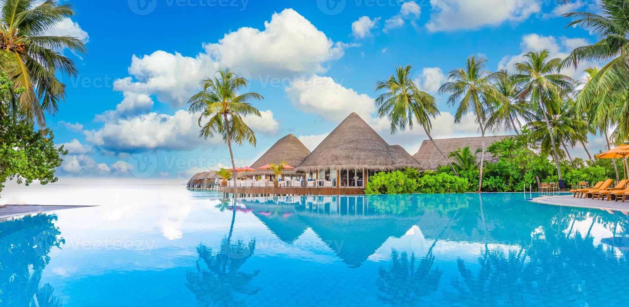 resort di lusso per vacanze estive con riflesso sulla piscina a sfioro, vista sul mare di palme. incredibile paesaggio di viaggio, foto