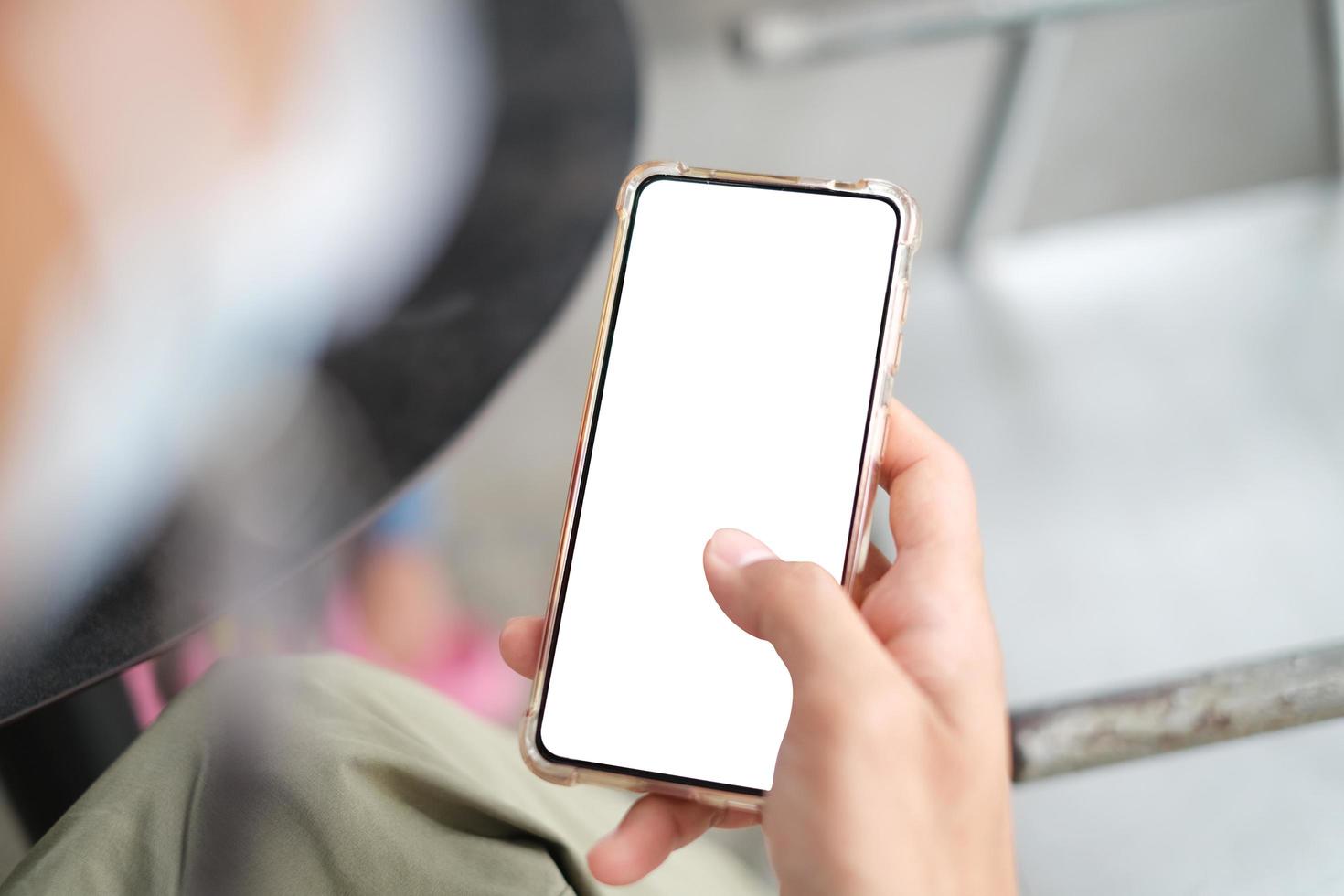 la mano ravvicinata utilizzando lo smartphone mostra lo schermo bianco per il design del tuo sito web, il logo, l'app con sfondo sfocato. foto