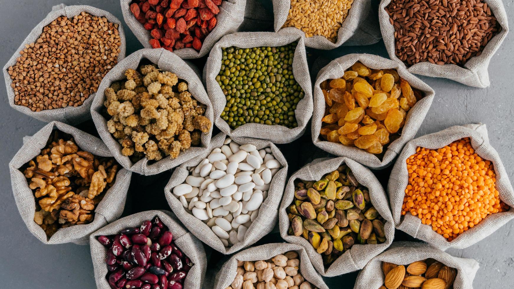 cereali vari e frutta secca in sacchi di tela di iuta sulla bancarella del mercato. vista dall'alto. set di prodotti biologici sani. concetto di alimentazione sana foto