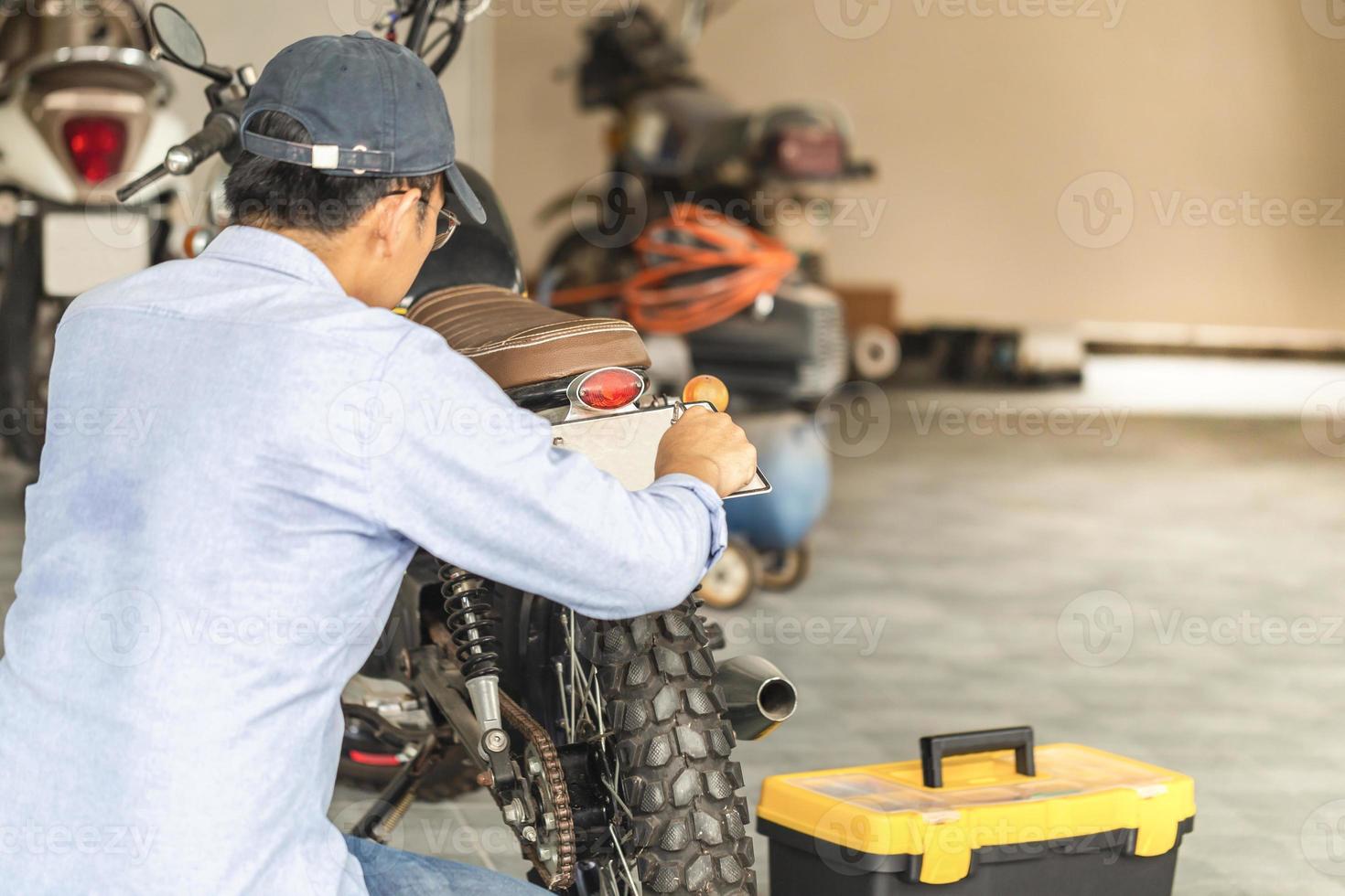 meccanico che ripara la moto nel garage dell'officina, uomo che ripara la motocicletta in officina, concetti di riparazione e manutenzione foto