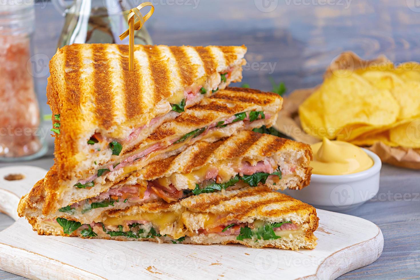 club sandwich con prosciutto, formaggio, pomodoro, insalata e patatine foto