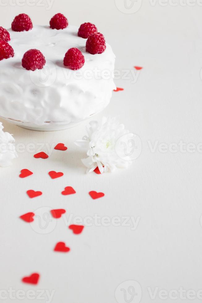 torta bianca con lamponi e cuori rossi foto