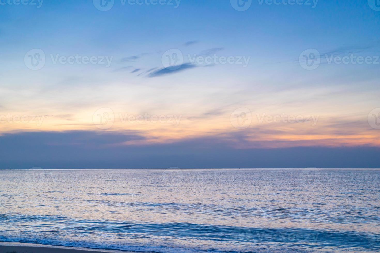 mare calmo con cielo al tramonto e sole tra le nuvole. sfondo oceano e cielo. tranquillo paesaggio marino. orizzonte sull'acqua. cielo al tramonto sul mare la sera con nuvole colorate luce solare arancione foto