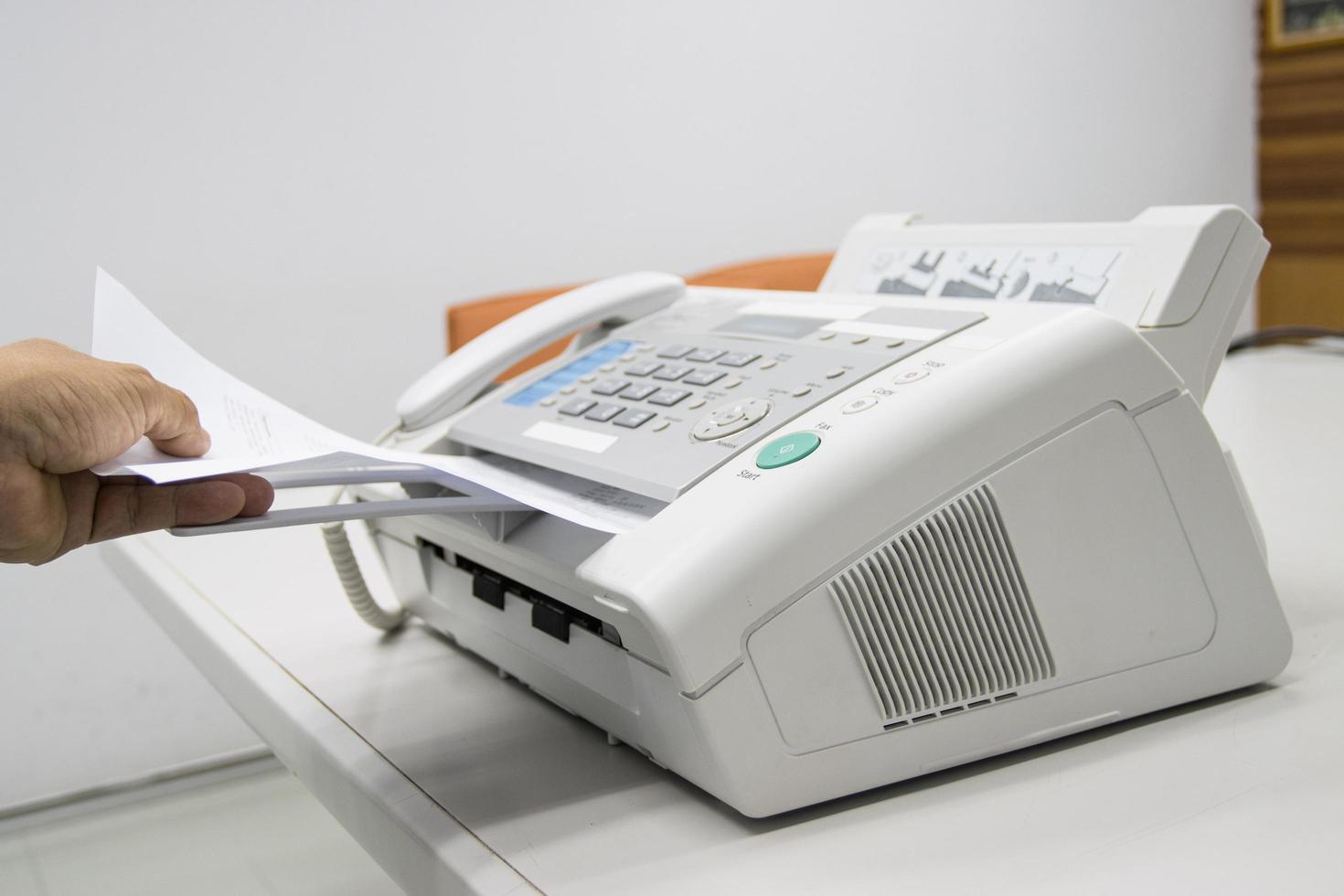 mano stanno usando un fax in ufficio, apparecchiature per la trasmissione di dati. foto