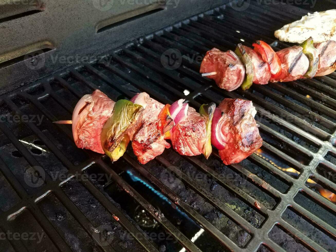 spiedini di manzo con cipolle e peperoni su un bastoncino su una griglia con pollo foto