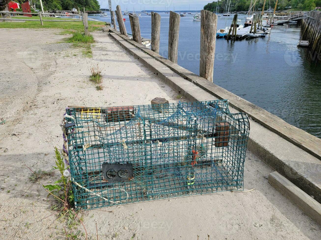 trappola per aragoste o gabbia sul molo con acqua e barche foto