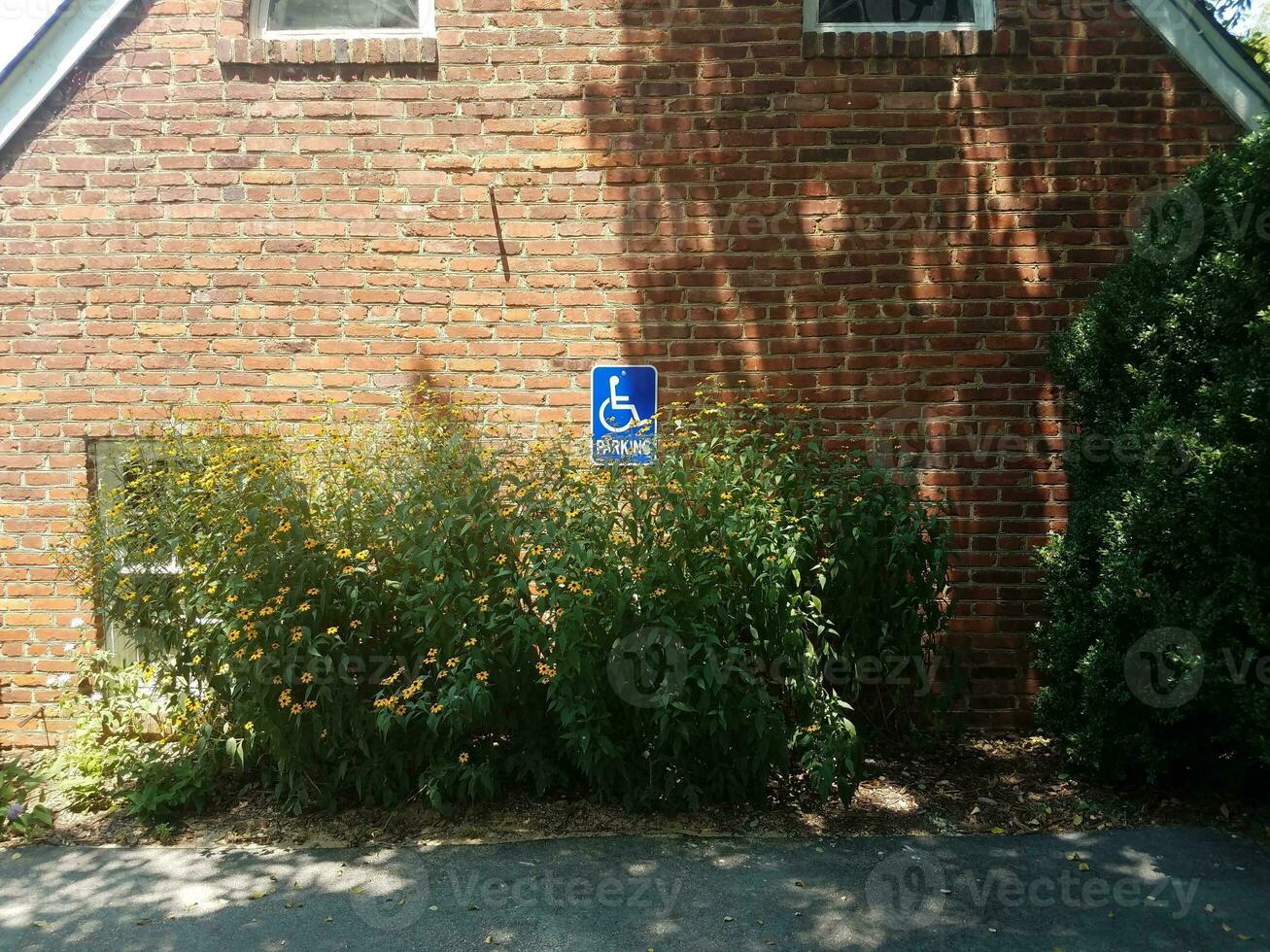 muro di mattoni rossi con cartello blu di parcheggio per disabili foto