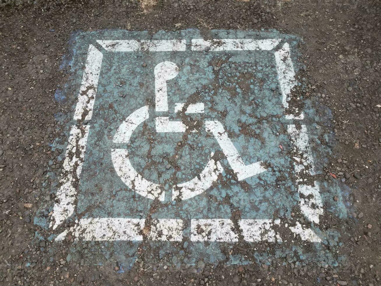 segno blu indossato della sedia a rotelle o dell'handicap sull'asfalto foto