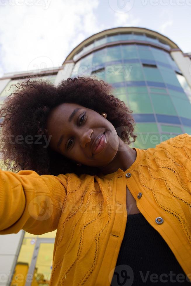 una donna afroamericana felice e giovane prende un selfie, primo piano foto