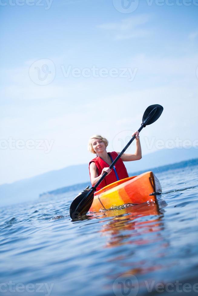 donna con giubbotto di sicurezza kayak da solo su un mare calmo foto