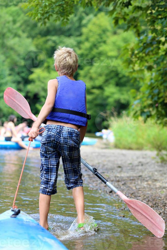 ragazzo attivo godendo kayak sul fiume durante il campeggio estivo foto