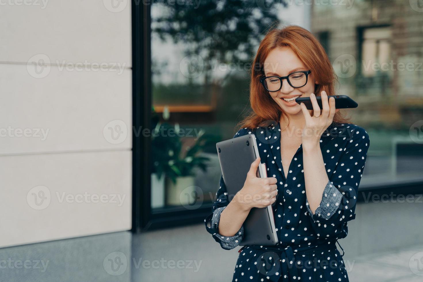 l'imprenditrice cammina all'aperto registra un messaggio vocale nei social media tramite smartphone foto