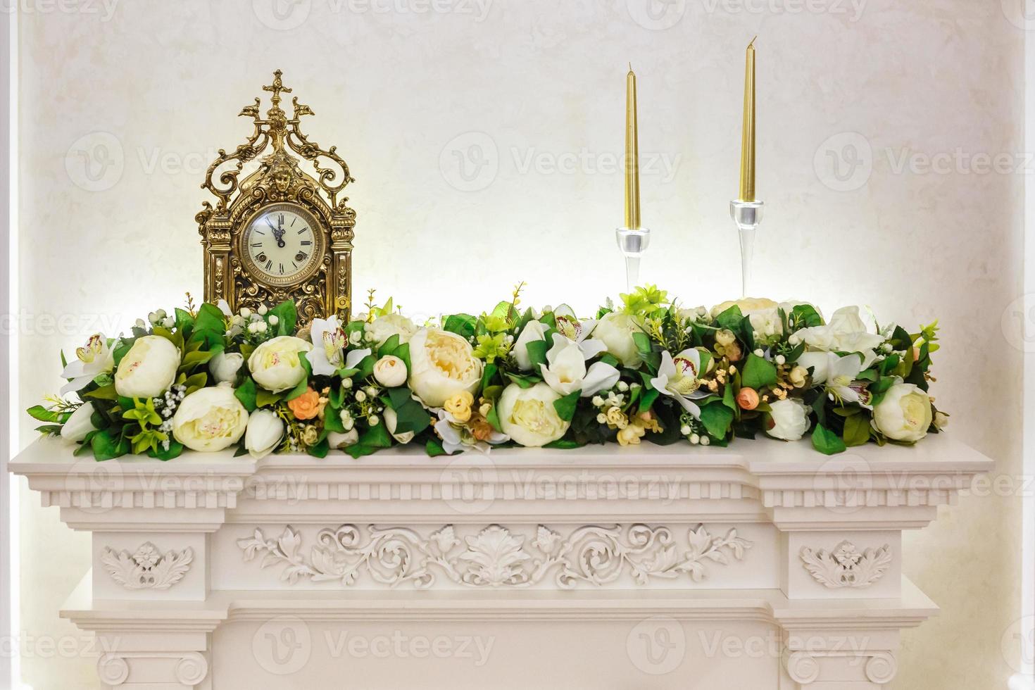 orologio antico con fiori su un tavolo con candele in tenue stile retrò vintage. foto