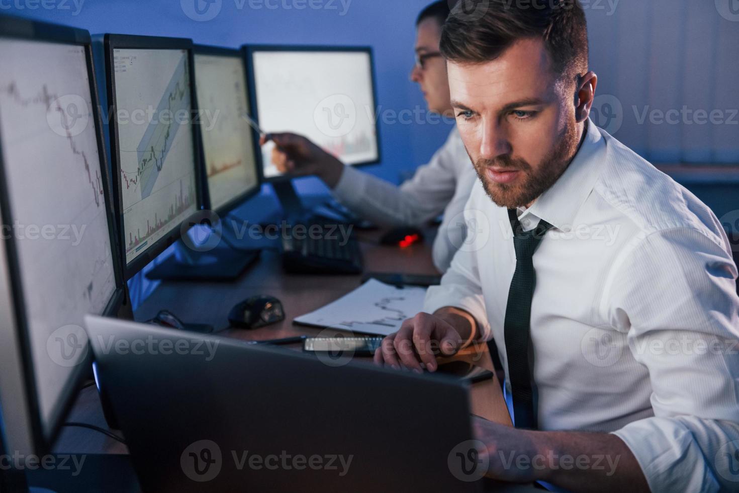 in abiti ufficiali. due operatori di borsa che lavorano in ufficio con la tecnologia di cambio foto