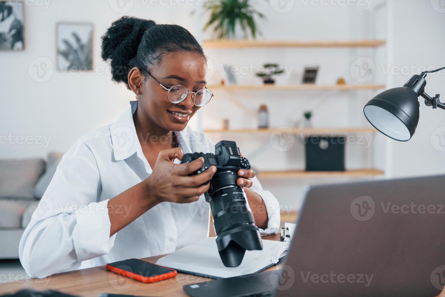 seduto a tavola. la giovane donna afroamericana in camicia bianca è a casa foto