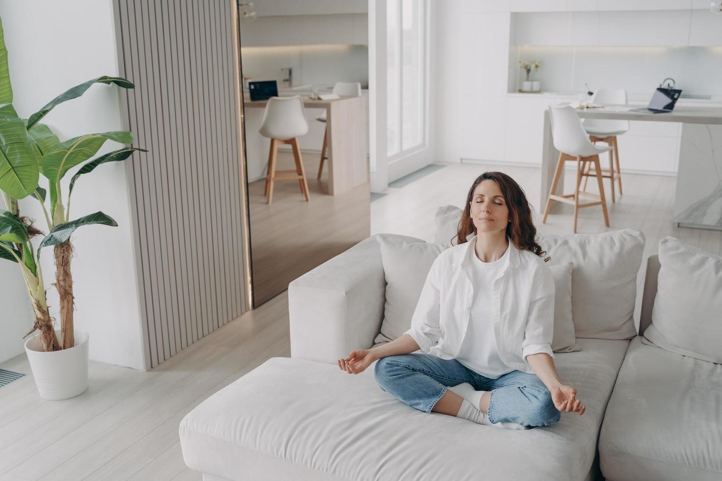 la giovane donna ispanica sta praticando yoga e meditazione a casa. benessere e routine mattutina. foto