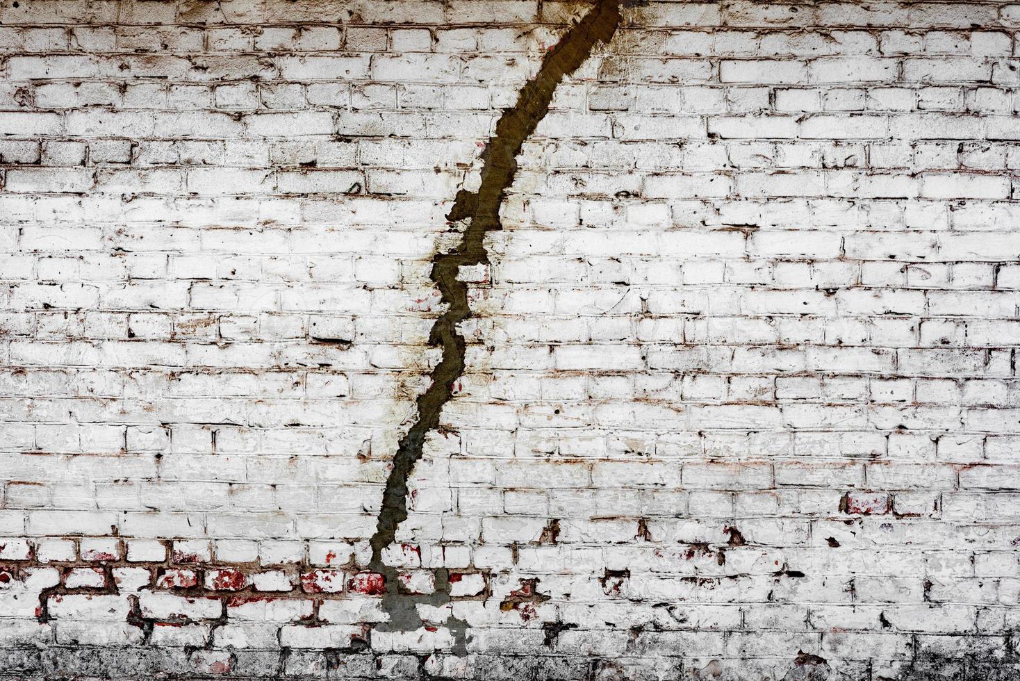 trama di un muro di mattoni con crepe e graffi che possono essere utilizzati come sfondo foto