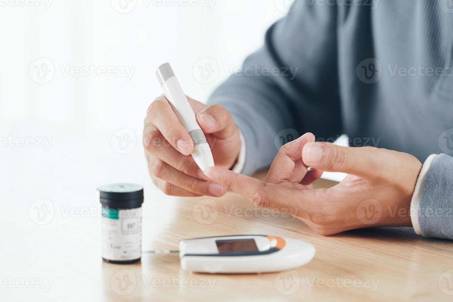 uomo asiatico che usa la lancetta sul dito per controllare il livello di zucchero nel sangue mediante glucometro, assistenza sanitaria e medica, diabete, concetto di glicemia foto