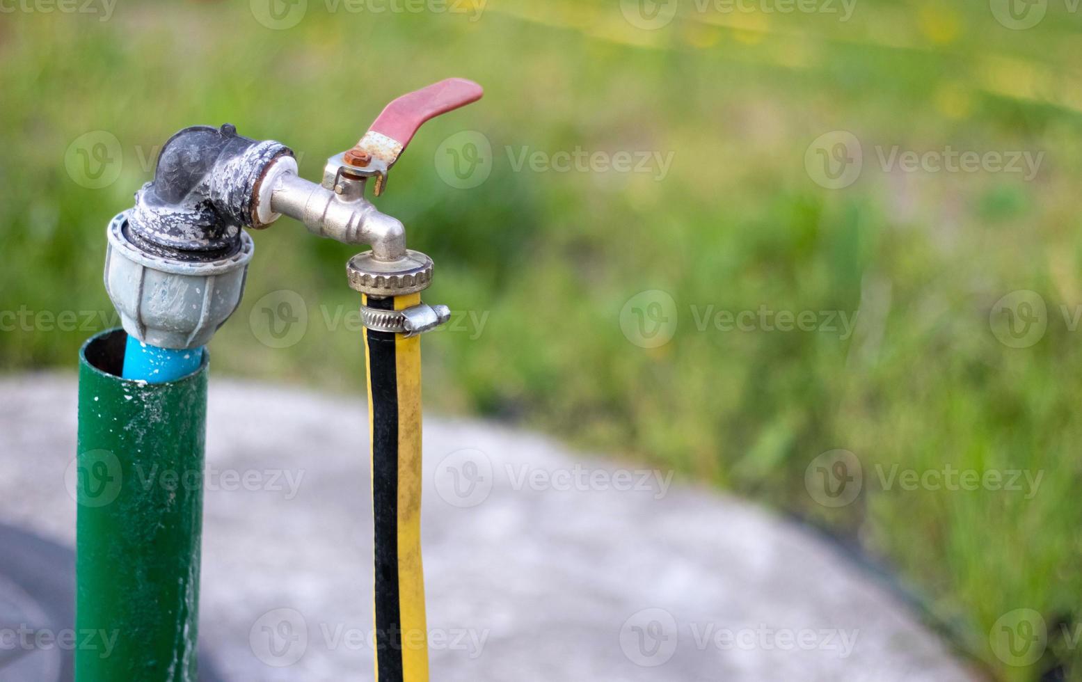 impianto idraulico, pompa dell'acqua da un pozzo. un rubinetto dell'acqua esterno con un tubo da giardino giallo attaccato ad esso. sistema di pompaggio dell'acqua di irrigazione per l'agricoltura. tubo in giardino per l'irrigazione, soleggiata giornata estiva. foto