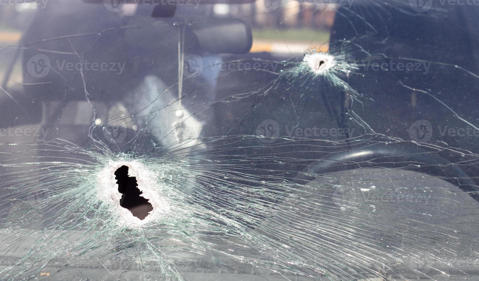 fori sul parabrezza dell'auto, è stato sparato da un'arma da fuoco. fori di proiettile. rompi il parabrezza dell'auto, auto rotta e danneggiata. il proiettile ha fatto un buco nel vetro. foto