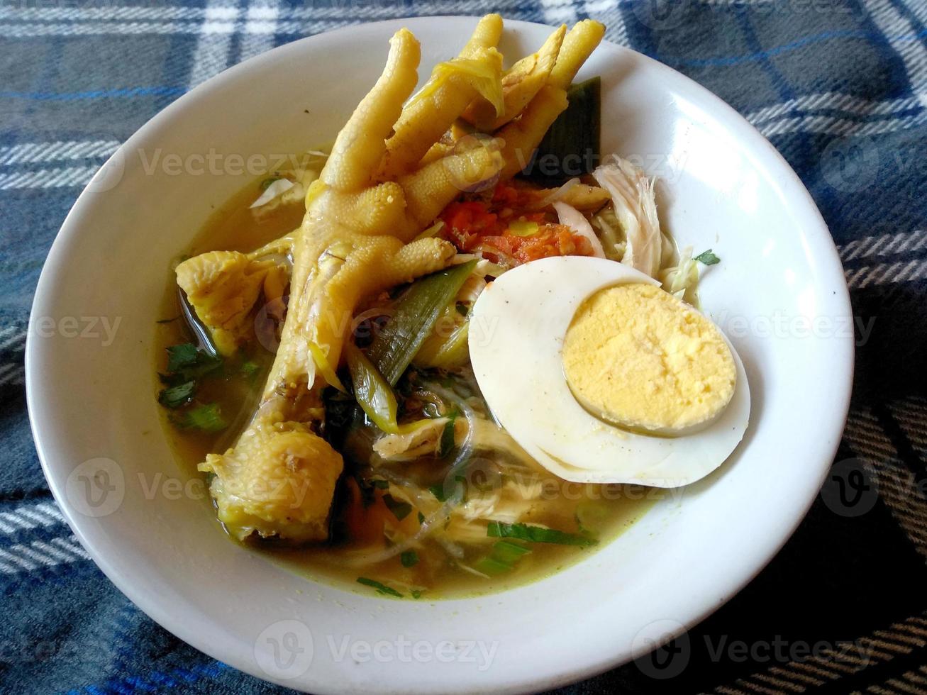 soto ceker ayam kuah kuning o soto zampe di pollo su una ciotola. cibo culinario indonesiano foto