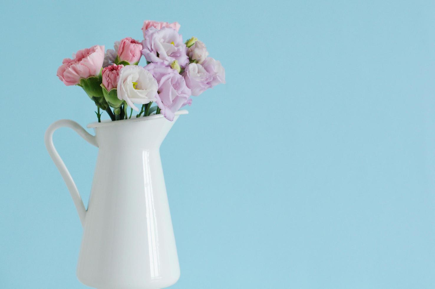 bellissimo garofano rosa e giallo e fiori viola di eustoma o lisianthus in vaso bianco. foto