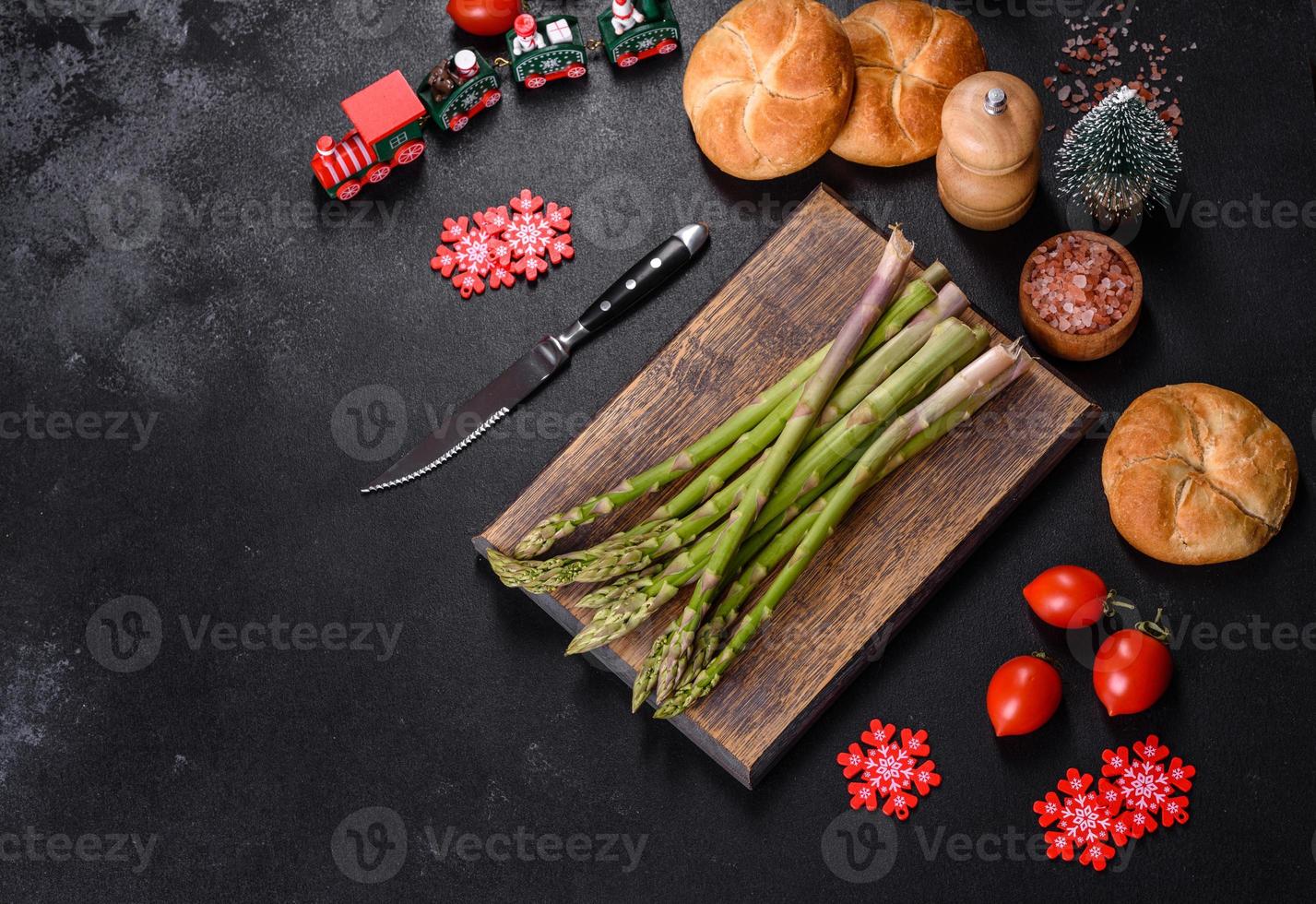 gambi di asparagi verdi crudi freschi deliziosi sul tagliere di legno foto