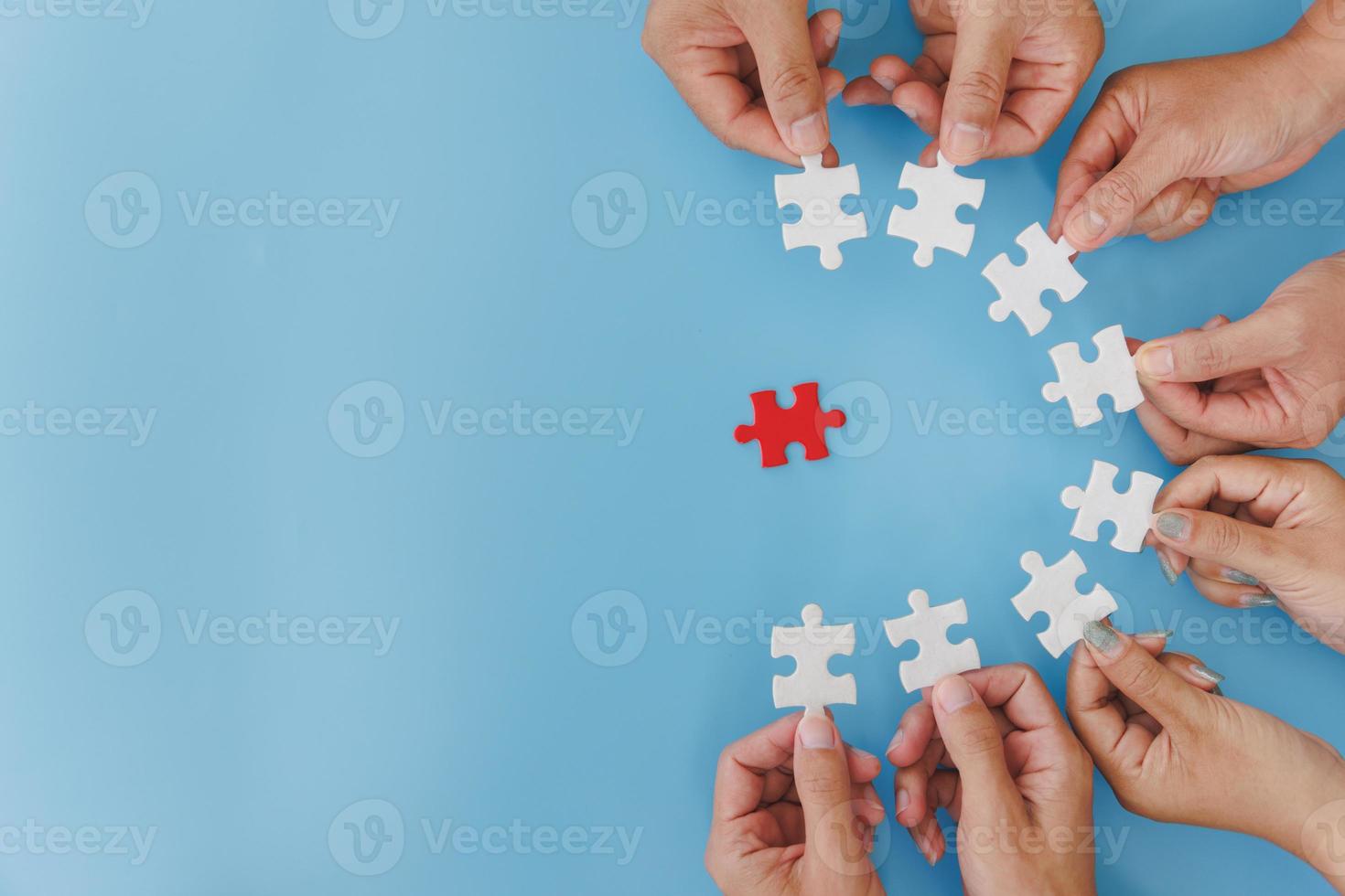 gruppo di uomini d'affari assembla puzzle su sfondo blu, lavoro di squadra, aiuto e supporto negli affari, simbolo di associazione e connessione. strategia d'affari. foto