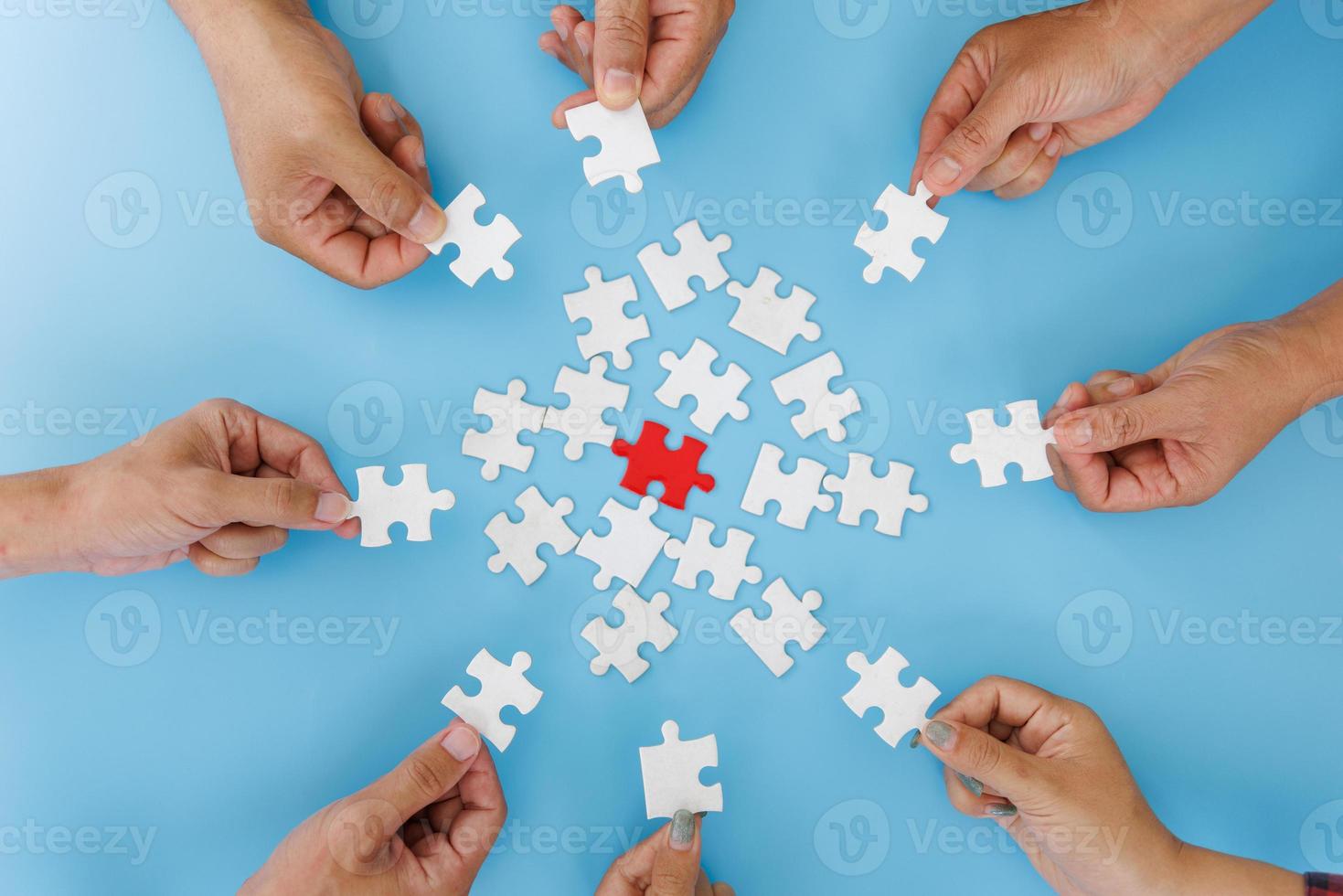 mani di persone diverse che assemblano puzzle, il team mette insieme i pezzi alla ricerca della giusta corrispondenza, aiuta il supporto nel lavoro di squadra per trovare un concetto di soluzione comune, vista ravvicinata dall'alto foto