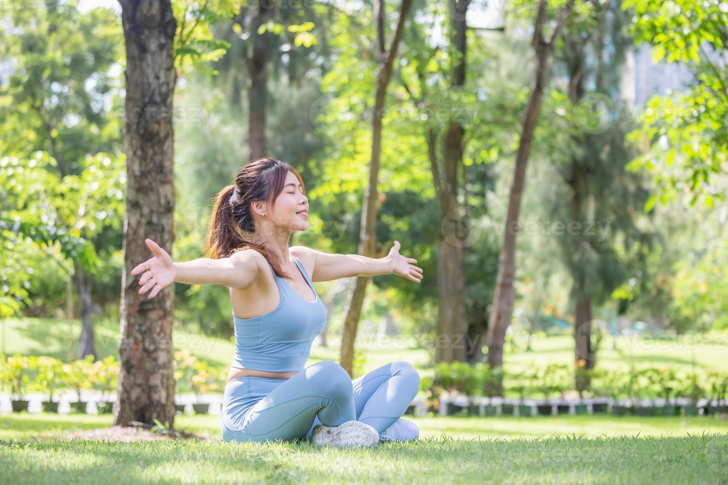 donna sportiva che respira aria profondamente fresca con le braccia alzate all'aperto nel parco foto