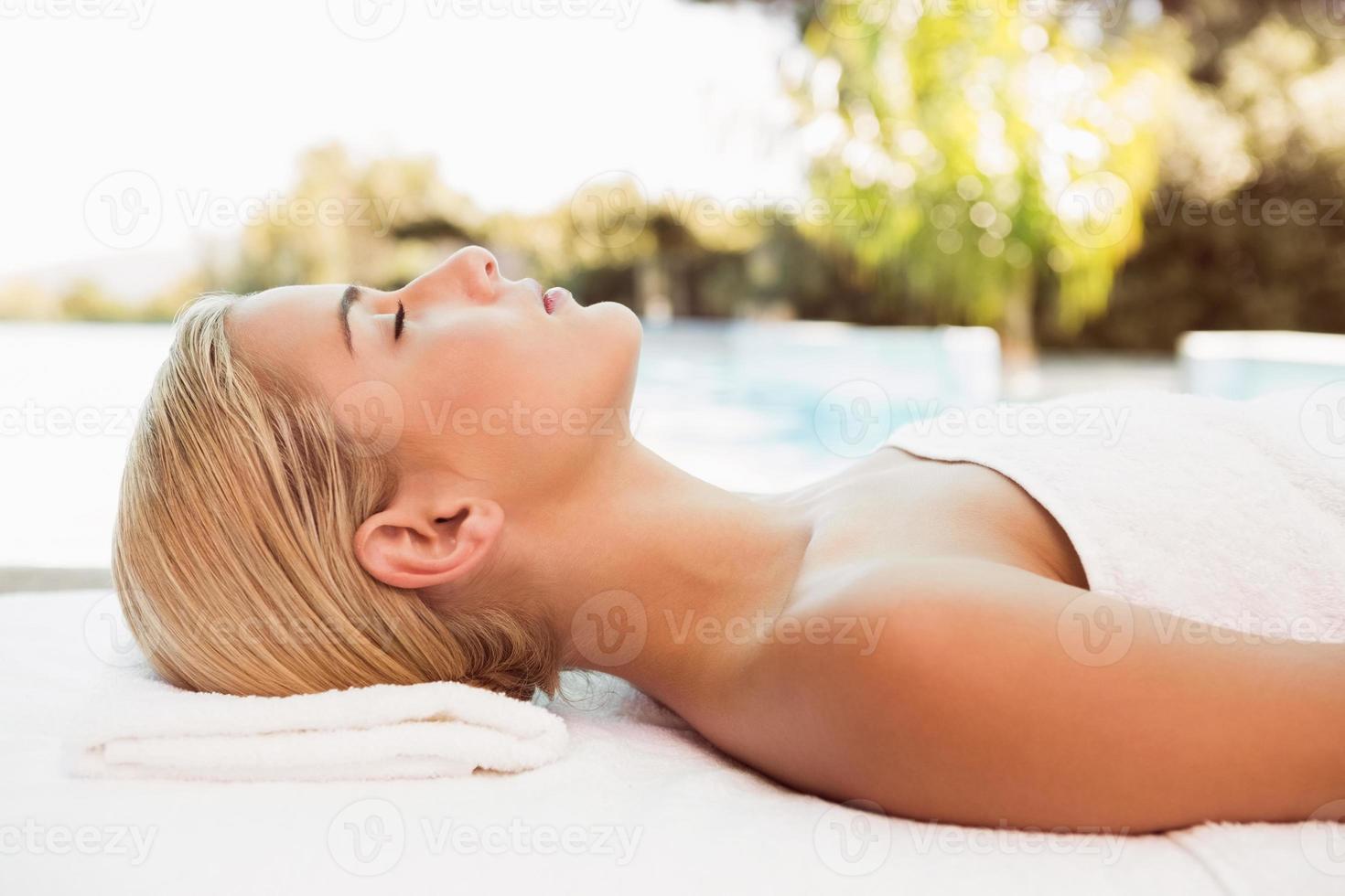 bella donna sdraiata sul lettino da massaggio al centro benessere foto