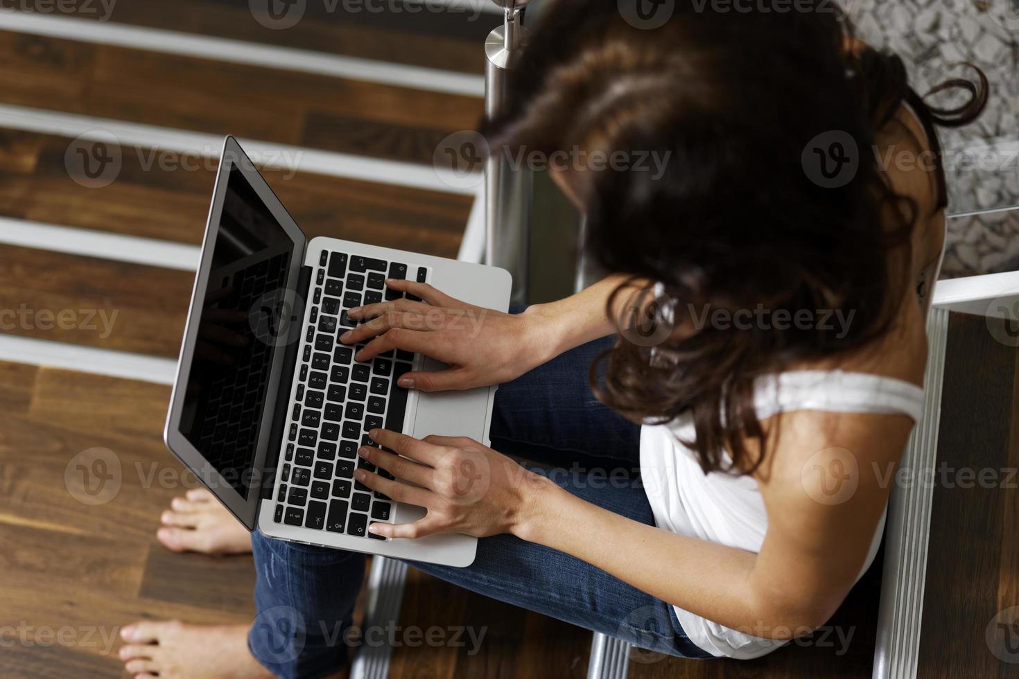 donna che per mezzo del computer portatile sulla scala foto