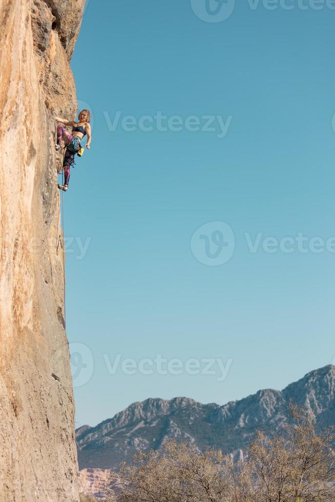 la ragazza sportiva è impegnata nell'arrampicata su roccia foto