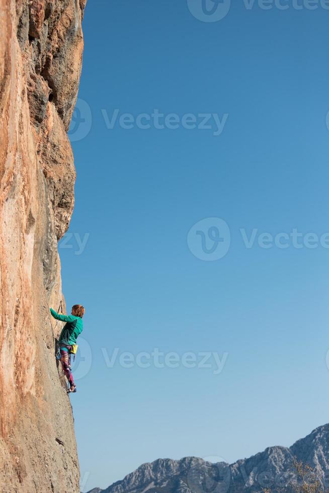 la ragazza sportiva è impegnata nell'arrampicata su roccia foto