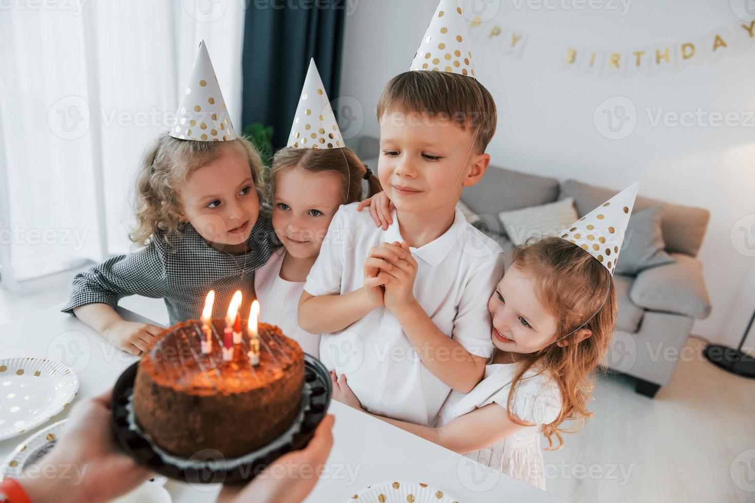 festeggiare il compleanno. donna che tiene la torta. gruppo di bambini è insieme a casa durante il giorno foto