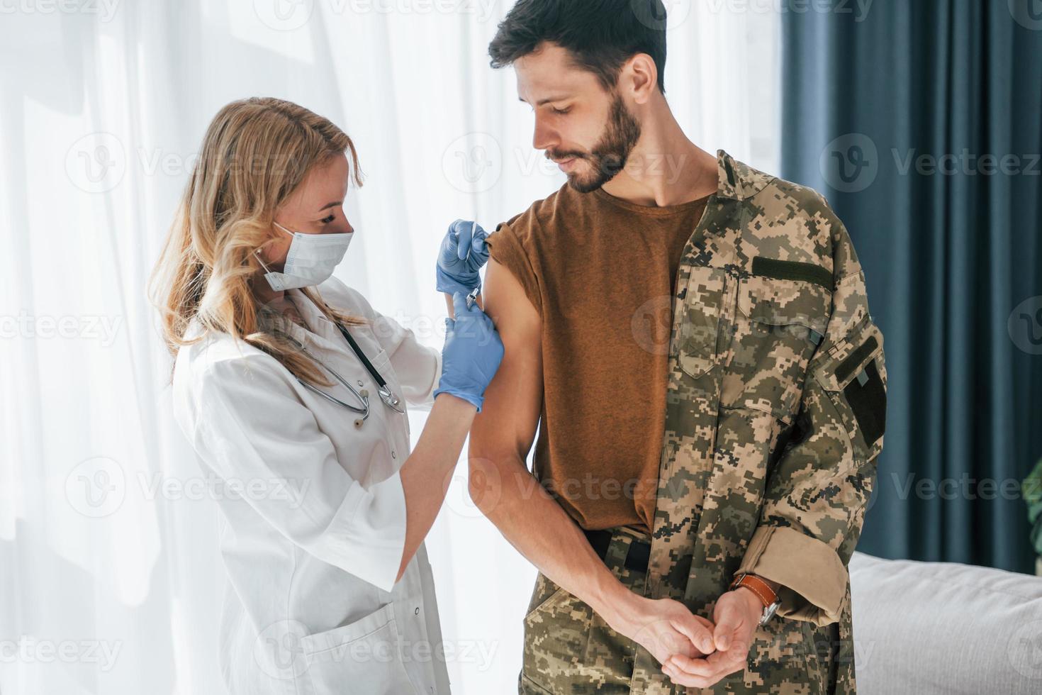 il soldato viene vaccinato da una dottoressa al chiuso foto