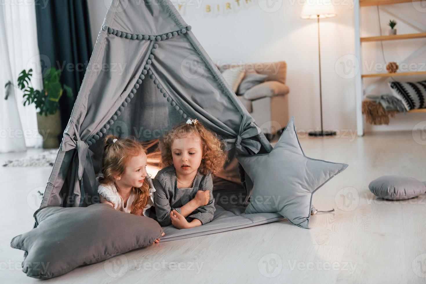 nella tenda. due bambini stanno insieme a casa durante il giorno foto