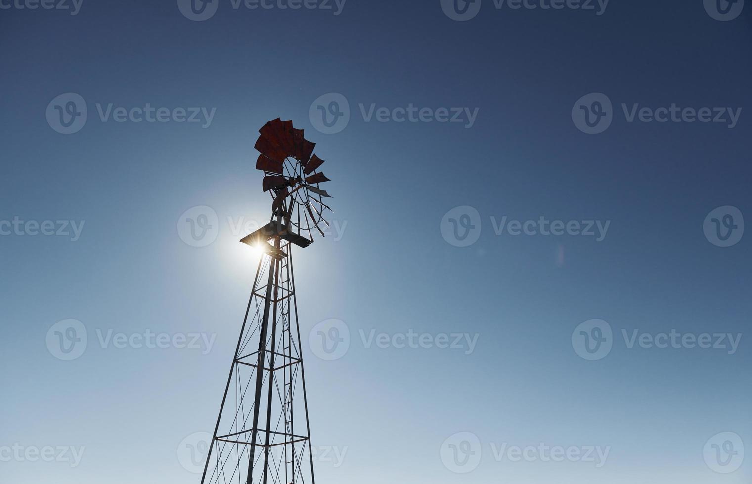 vista del mulino a vento che è contro il cielo azzurro con luce solare foto