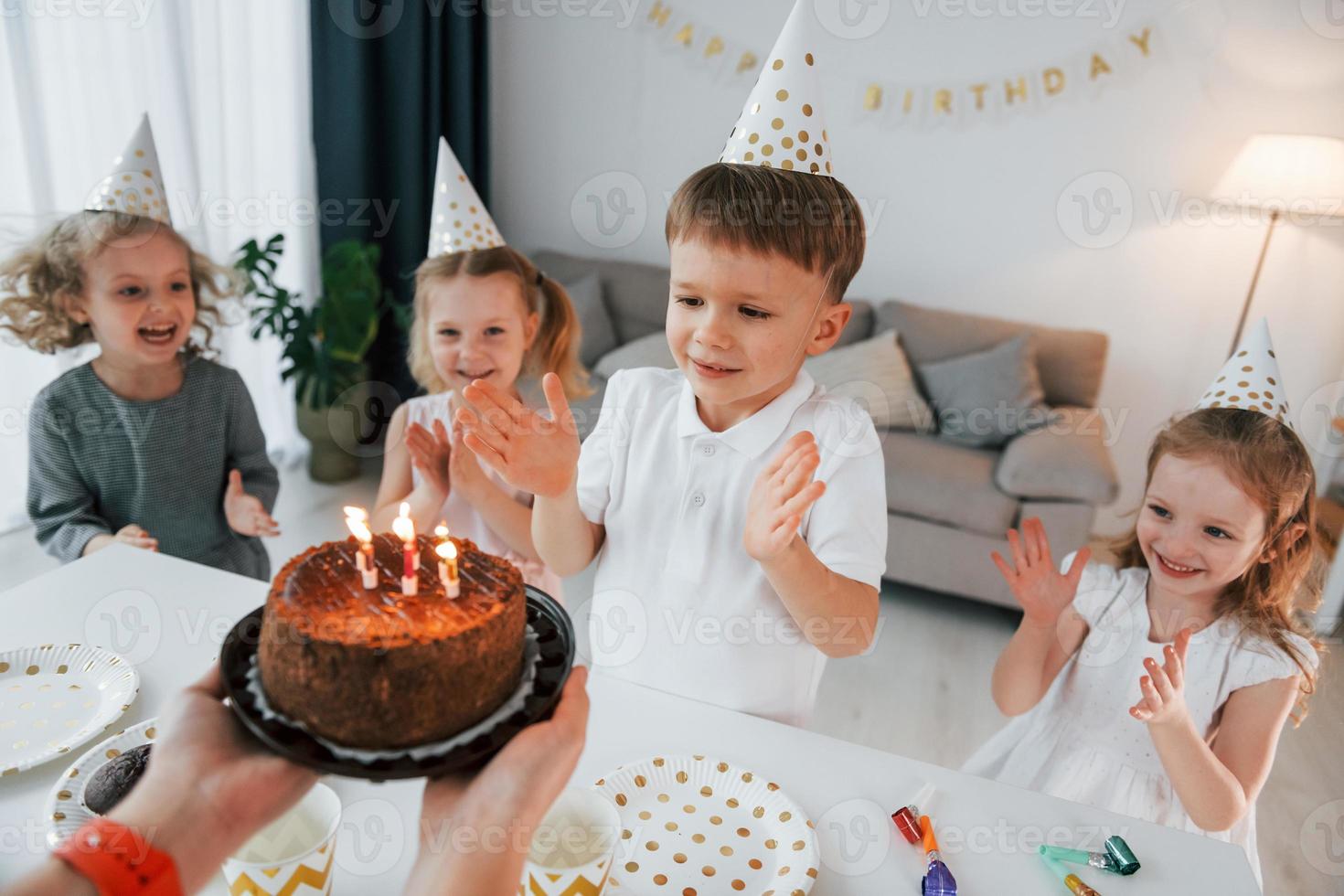 festeggiare il compleanno. donna che tiene la torta. gruppo di bambini è insieme a casa durante il giorno foto